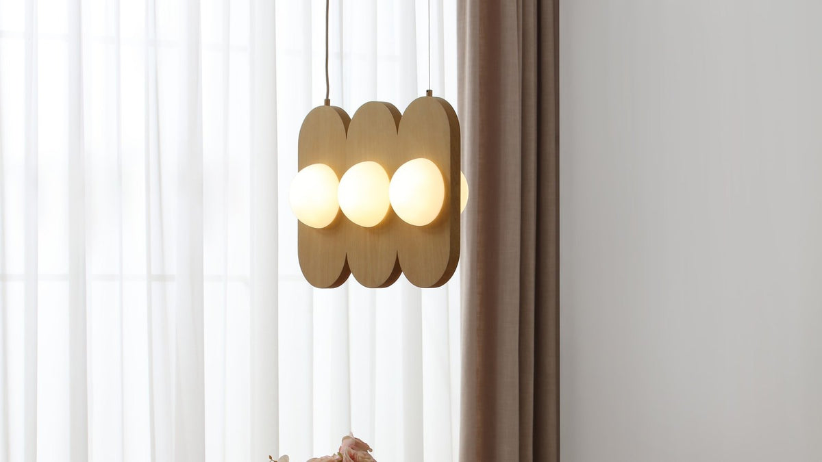 A lit linear multi-globe pendant hanging over a wood dining table
