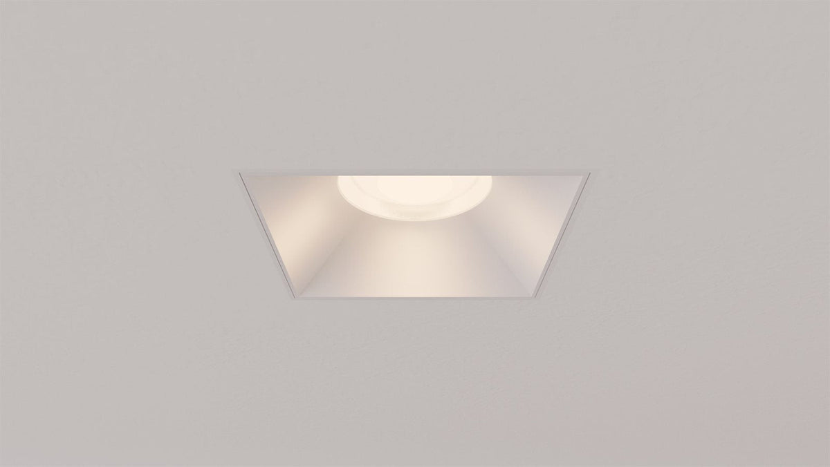 A lit Libra square trimless recessed downlight centered in a ceiling, warm low-glare beam