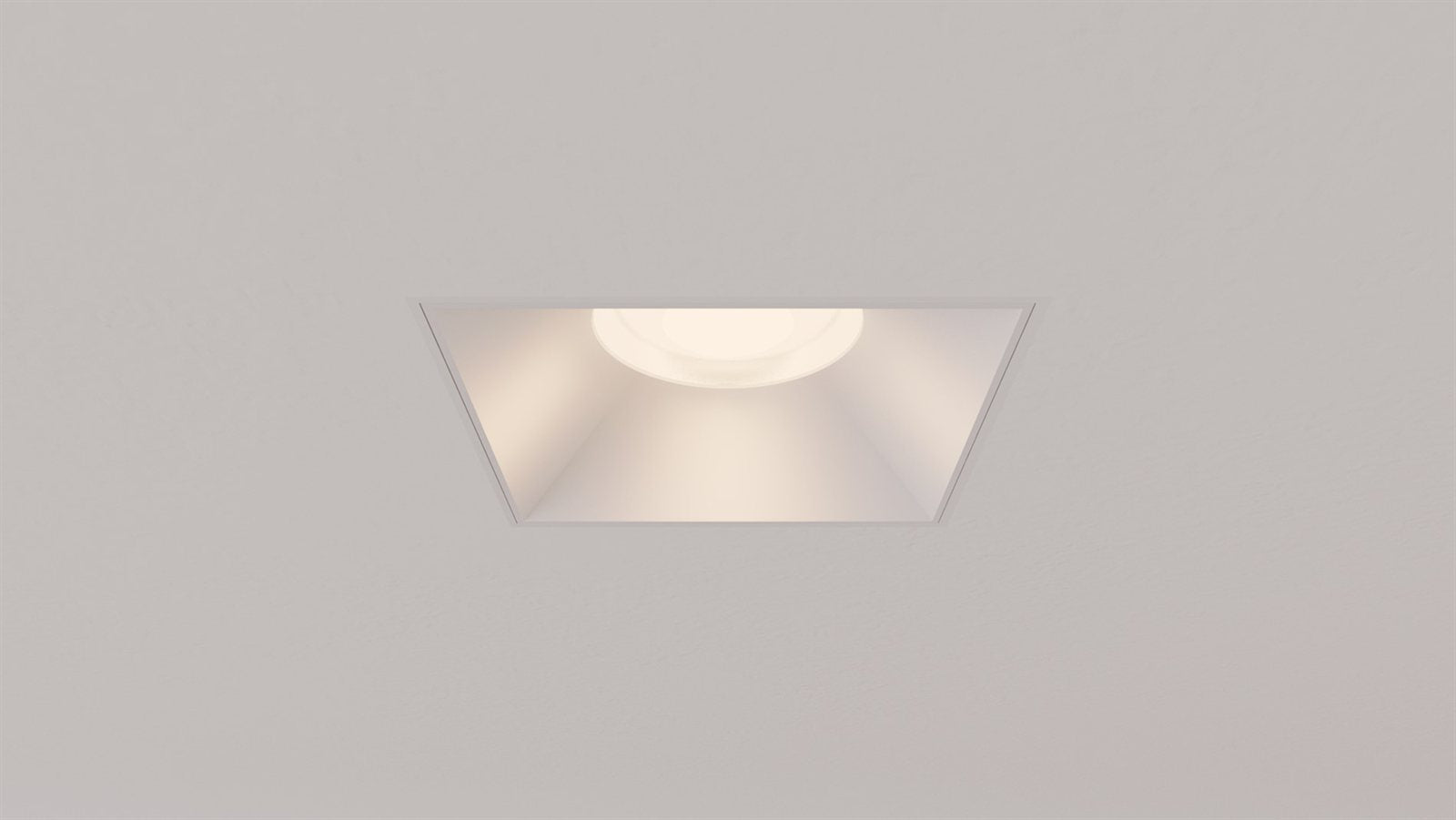 A lit Libra square trimless recessed downlight centered in a ceiling, warm low-glare beam