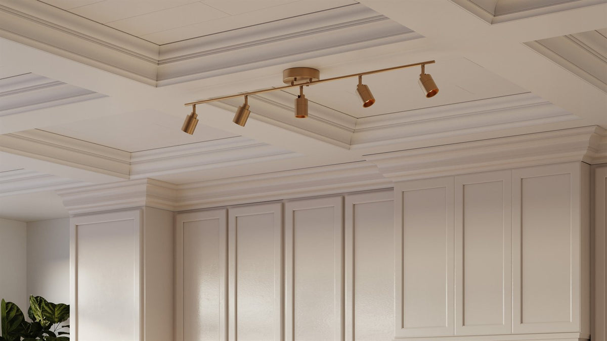 A brushed brass Shura five-head track light centered on the coffered ceiling of a designer kitchen