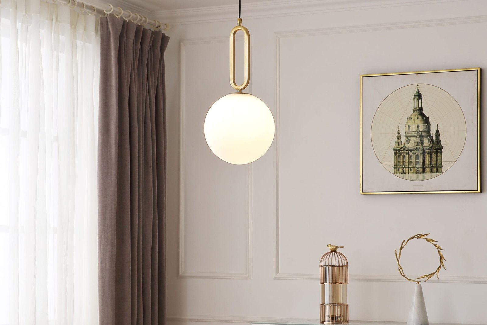 A brass and opal glass globe pendant lit above a round marble dining table